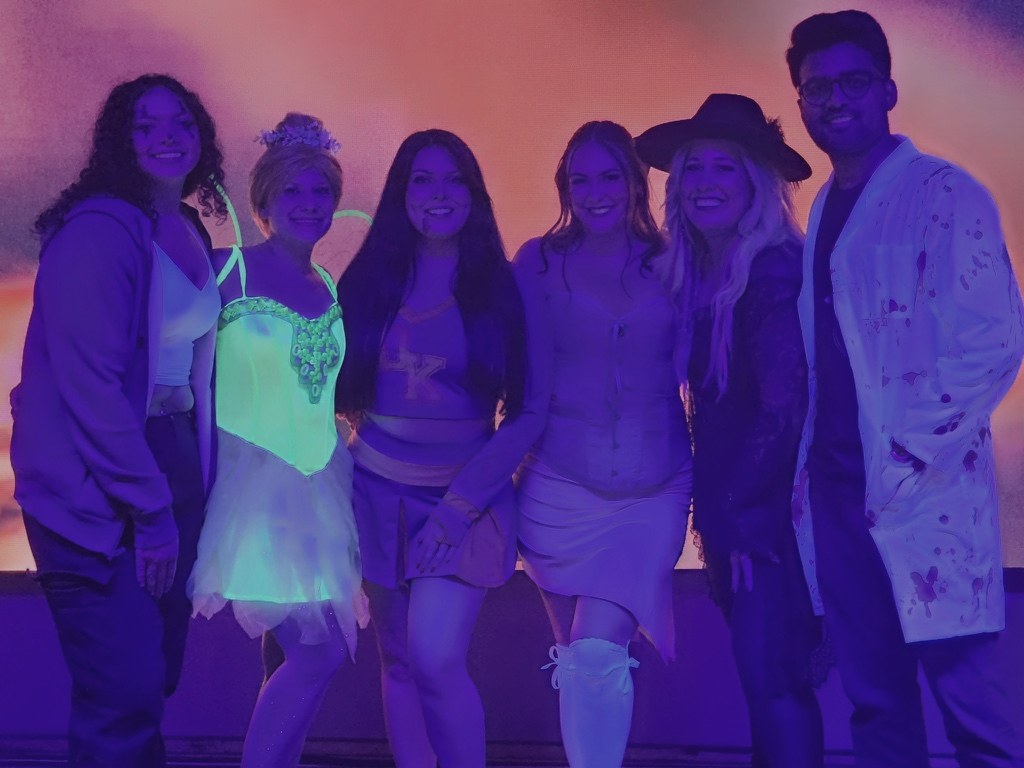The team in glowing Halloween costumes at an event.